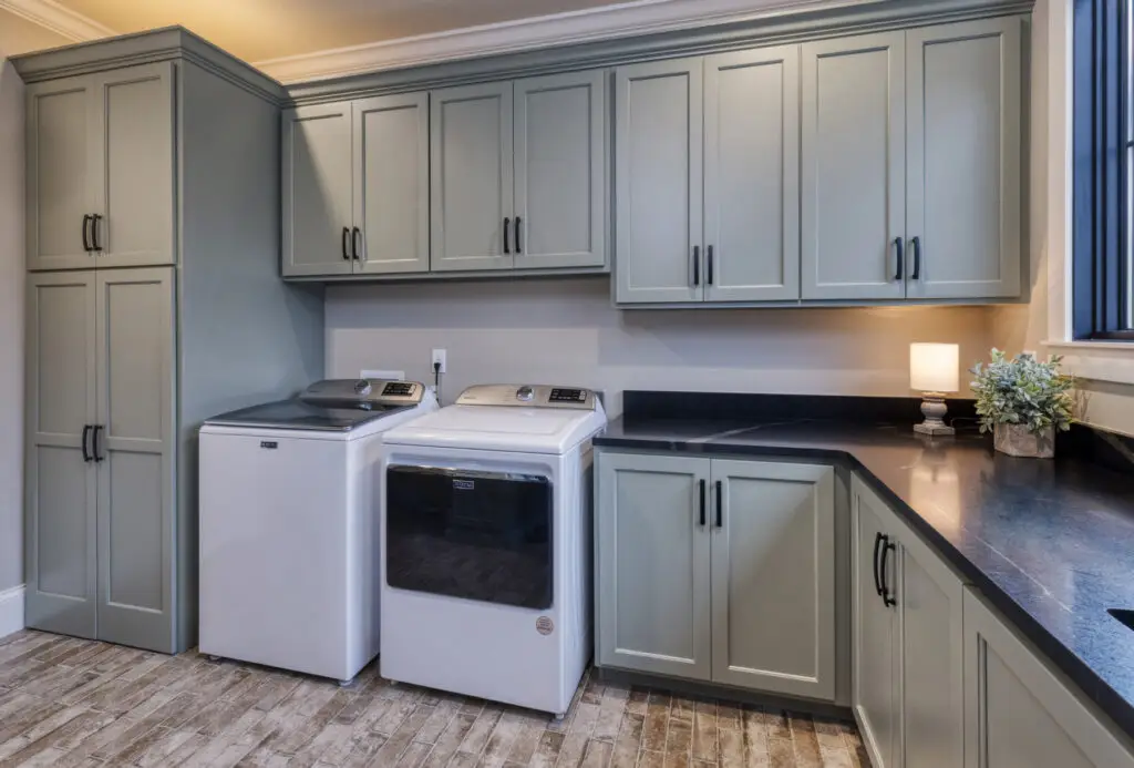 laundry room with sage painted cabinets with black handles