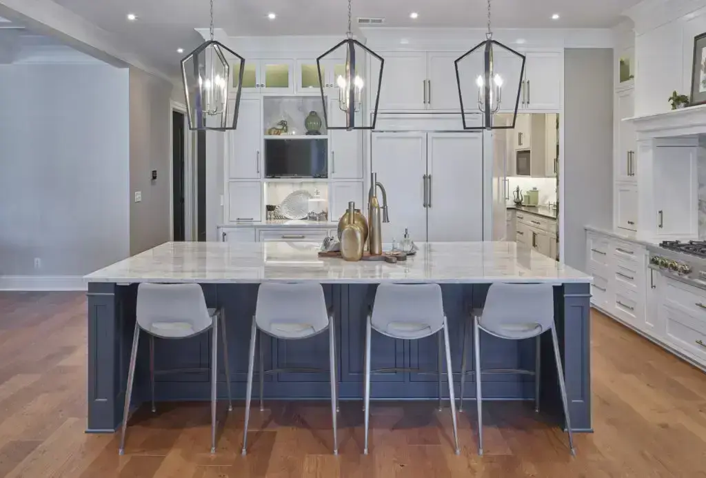home kitchen with three pendant lights, four stools for middle island and white cabinets.