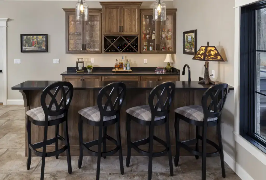 in-home bar with brown wood cabinets and 4 stools