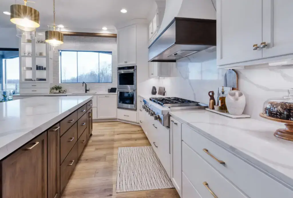 big white minimalist kitchen with both wood cabinets and white cabinets with gold handles.